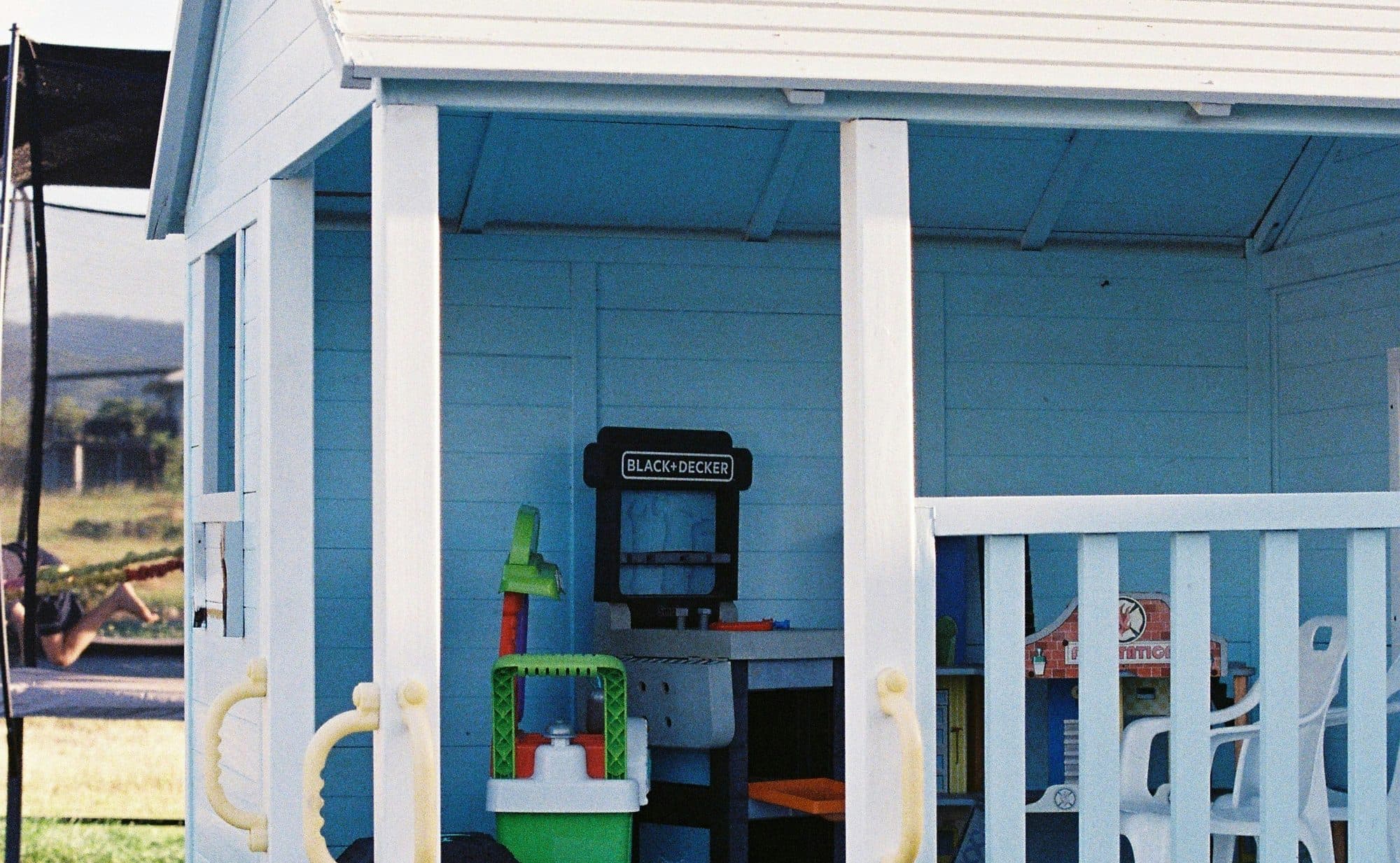 A raised backyard cubby house with a play kitchen and toys set up underneath
